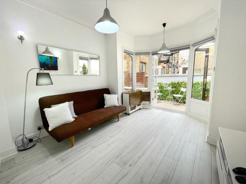伦敦LUXURIOUS Terrace 2 Bedrooms in Relaxing Covent Garden Apartment的客厅设有棕色的沙发和一些窗户