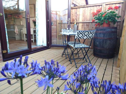 金斯林Avocet Lodge, Snettisham的一个带蓝色鲜花和椅子的门廊和桶子