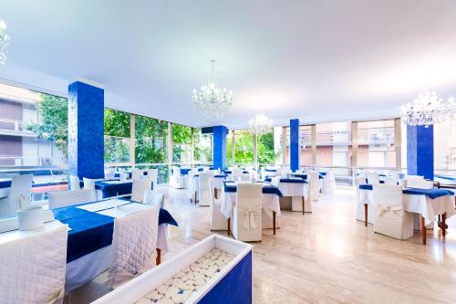 里米尼Mantovani Hotel Murano & Mariù的餐厅设有白色的桌椅和窗户。