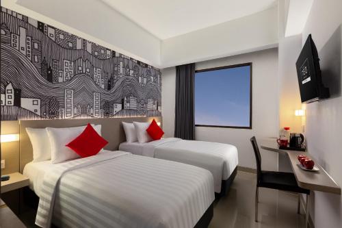 梭罗Hotel Neo Gading Solo的两张位于酒店客房的床铺,配有红色枕头