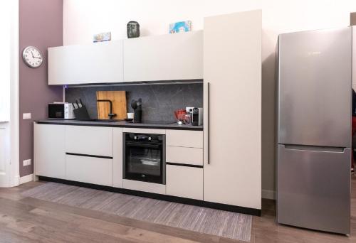 米兰Household Settembrini的厨房配有白色橱柜和冰箱。