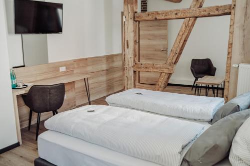 GroßwallstadtGasthaus Zum Adler的一间设有3个白色床垫和桌椅的房间