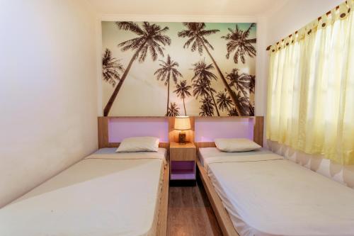 库塔Segara Sadhu Inn Kuta by ecommerceloka的墙上棕榈树间内的两张床