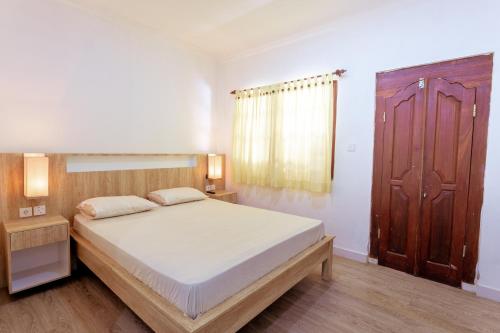 库塔Segara Sadhu Inn Kuta by ecommerceloka的一间卧室设有一张大床和一扇木门