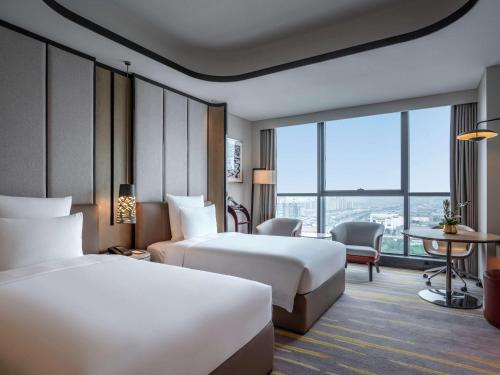 苏州苏州中惠铂尔曼酒店的酒店客房设有两张床和一张桌子。