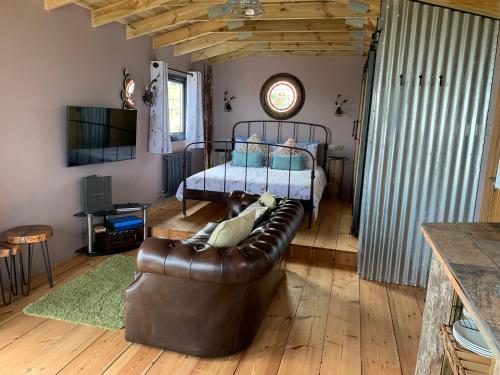 卡迪根Byre Cottages & Log Cabin的客厅配有真皮沙发和床。