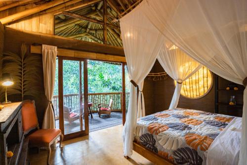 乌布Bamboo Turtles Ecolodge的一间卧室设有一张天蓬床和一个阳台