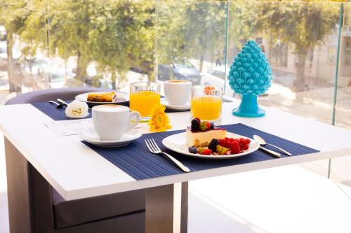 加利波利POPULA - The Lifestyle Hotel的餐桌,早餐包括蛋糕和橙汁