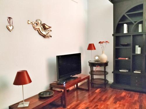 拉文纳Residenza Santi Muratori的客厅配有电视和带台灯的桌子