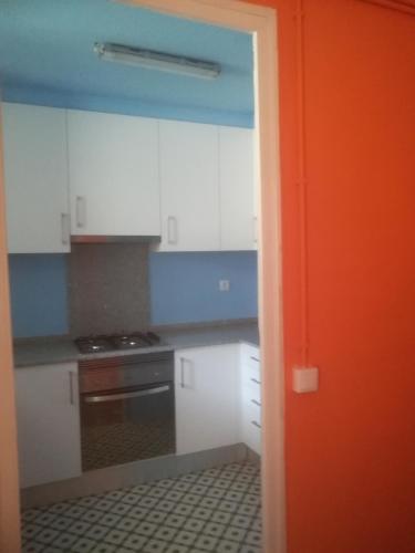 曼雷沙Pis Cèntric的厨房配有白色橱柜和橙色门