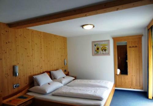 普雷格拉滕噶斯特豪斯考尼旅馆的一间带两张床铺的卧室,位于带木墙的房间内