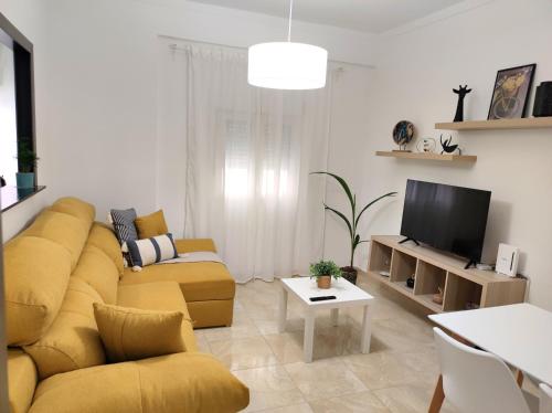 马拉加La Brisa apartamento的客厅设有黄色沙发和电视