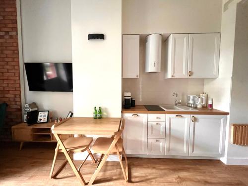 弗罗茨瓦夫Brick Castle - Apartament Ulrich的厨房配有白色橱柜和木桌