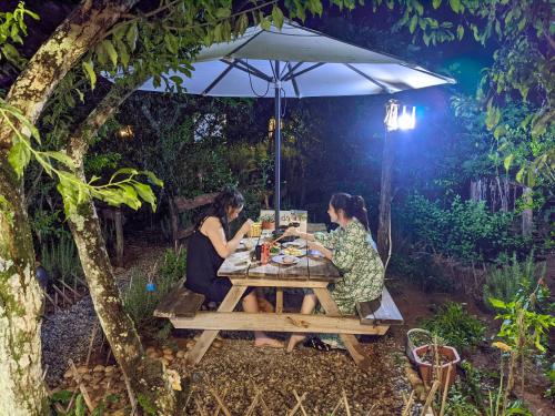 木州县Plum Hill - Moc Chau的两个坐在野餐桌上,坐在伞下