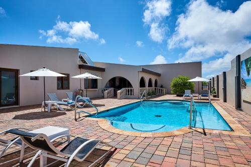 棕榈滩Bubali Luxury Apartments - Adults Only - Wheelchair Friendly的房屋旁的游泳池配有椅子和遮阳伞