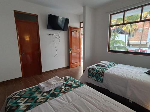 哈恩Hotel El Bosque的客房设有两张床和一台墙上的电视。