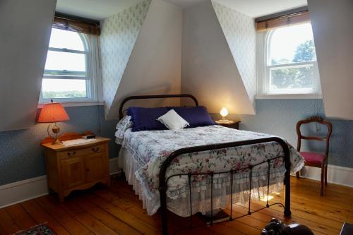 New GlasgowThe New Glasgow Inn的一间卧室配有一张床和一把椅子,还有两个窗户