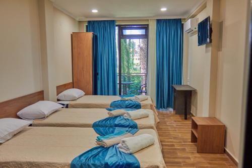谢赫维蒂利Villa Story Hotel的一间设有蓝色窗帘的房间,里面设有四张床铺