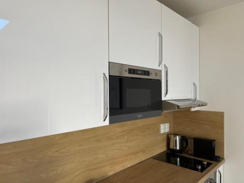 霍穆托夫ne-doma的厨房配有白色橱柜和黑微波炉