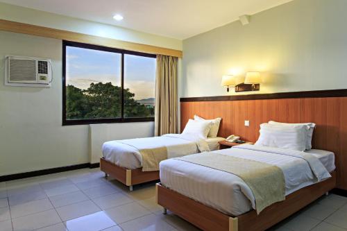 宿务果园宿务套房酒店的酒店客房设有两张床和窗户。