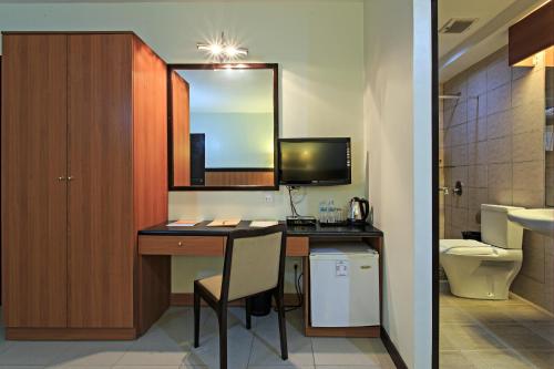 宿务果园宿务套房酒店的浴室配有带水槽和卫生间的书桌。