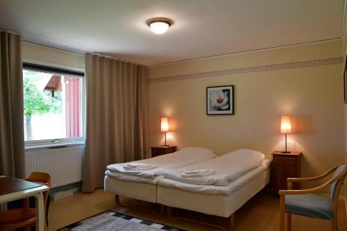 维辛瑟Wisingsö Hotell的一间卧室配有一张床、一个窗口和两盏灯。