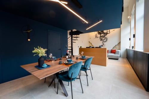 蒙斯Atypique LOFT Mons City Center的一间拥有蓝色墙壁和一张木桌及椅子的用餐室