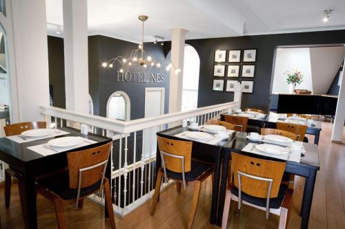 阿姆斯特丹纳斯酒店的一间用餐室,配有黑色的桌子和椅子