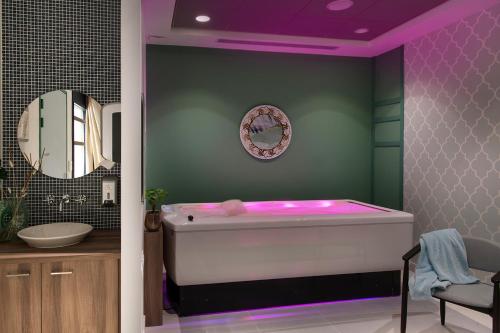 迪涅莱班Résidence services seniors DOMITYS LES EAUX VIVES的浴室配有浴缸和紫色照明