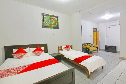 登巴萨OYO 3244 Grand Chandra Hotel的一间卧室配有两张红色和白色床单