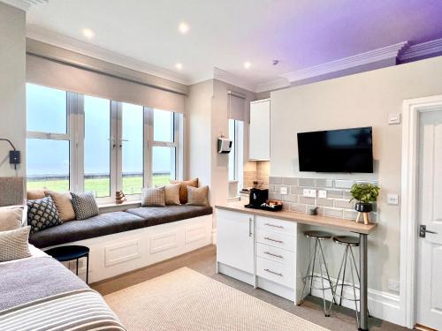 Littlestone-on-SeaBeachfront Compact Coastal Crib, DIRECT Sea Views & Air Conditioning的一间带沙发的卧室和墙上的电视
