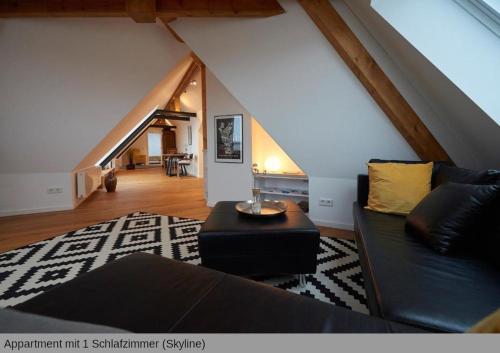 汉诺威Lofts in Hannover的客厅设有黑色沙发和楼梯。