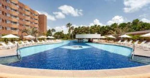 巴雷里尼亚斯GRAN LENÇÓIS FLAT - APTO PARTICULAR的一个带白色椅子的大型游泳池和一间酒店