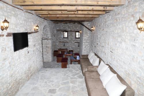 培拉特Villa Athina in Berat Castle - Since 1741的一间带沙发的石墙和电视的房间