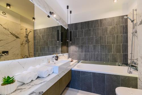 布拉索夫Luxury Landing Apartments Complex Qualis Brasov的浴室配有2个盥洗盆、浴缸和浴缸。