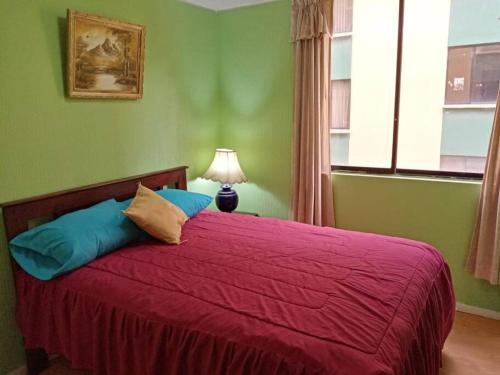 基多Hermoso Apartamento al Norte cerca de la Embajada Americana的一间卧室配有一张带红色棉被的床和窗户。