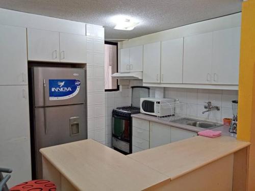 基多Hermoso Apartamento al Norte cerca de la Embajada Americana的厨房配有白色橱柜和带微波炉的台面。