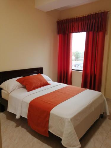 弗朗西斯科德奥雷利亚纳港Hotel Torre Orquídea的一间卧室配有一张带红色窗帘的床和一扇窗户