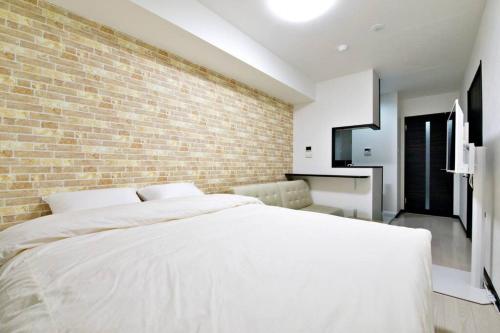 东京Green Sea Oshiage的卧室配有白色的床和砖墙