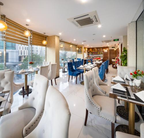 岘港Menora Premium Da Nang - Sea Corner Boutique的一间设有白色椅子、桌子和窗户的餐厅