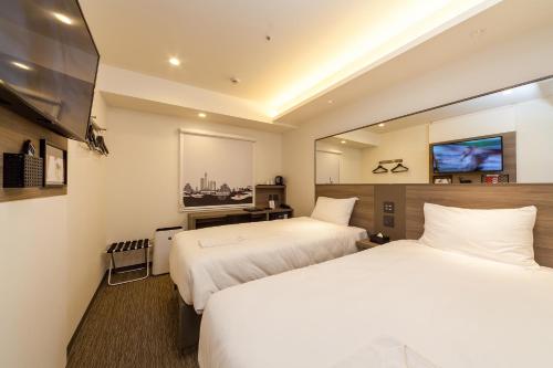 广岛Smile Hotel Hiroshima的酒店客房设有两张床和一台平面电视。