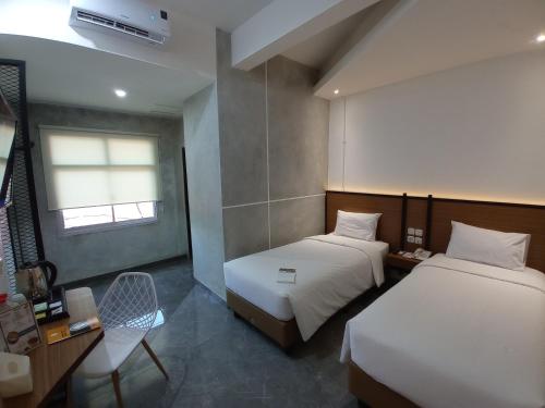 Talang KelapaRid's Hotel Palembang的客房设有两张床、一张桌子和一把椅子。