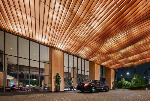 吉隆坡吉隆坡宾乐雅臻选酒店的停车场在一座拥有木制天花板的建筑前