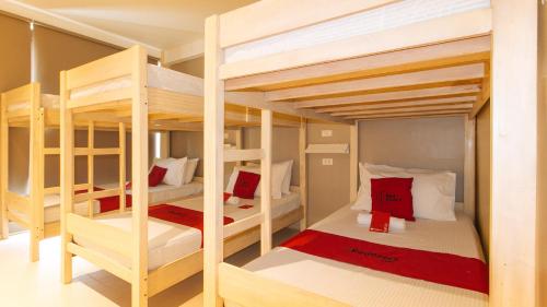 圣胡安RedDooorz @ Laiya Vivo Hotel Batangas的客房配有4张双层床,提供红色和白色的枕头