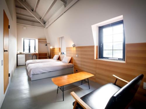 奄美Denpaku Amami Hotel的卧室配有1张床、1张桌子和1把椅子