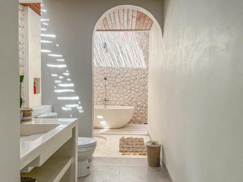 乌鲁瓦图Moana Villa & Suites Bingin的带浴缸、盥洗盆和卫生间的浴室