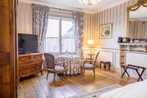 翁弗勒尔Le Manoir des Impressionnistes - Bord de Mer的酒店客房设有电视和桌椅