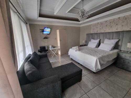 范德拜尔帕克016 Guest House的一间卧室配有一张床、一张沙发和一台电视。