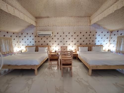 乌代浦Hill View Resort by Rudrakshi的一间卧室配有两张床和一张桌子及椅子