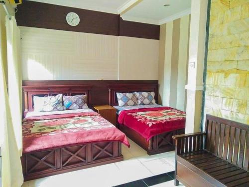 庞岸达兰Hotel Abad Baru 1的一间卧室设有两张床,墙上挂着一个时钟。